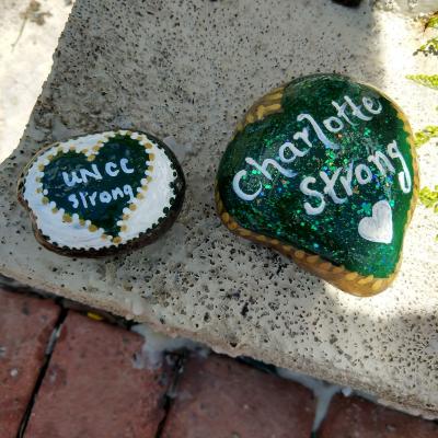 Stones painted with the words Charlotte Strong and UNCC Strong