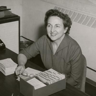 Bonnie Cone sitting at her desk, 1958