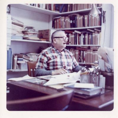 Harry Golden working at his desk smoking a cigar