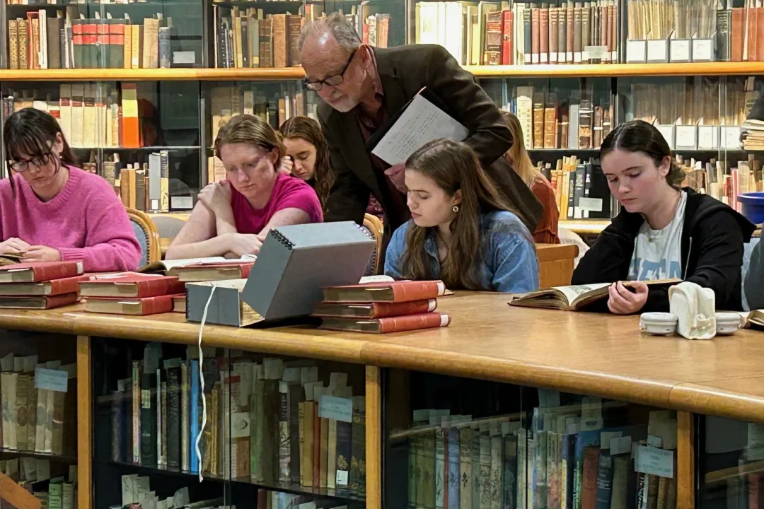 Prof. West and students look at books